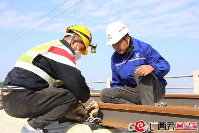 贵南高铁铺轨施工队队长张根全（右）在固定钢轨的螺丝进行检查。