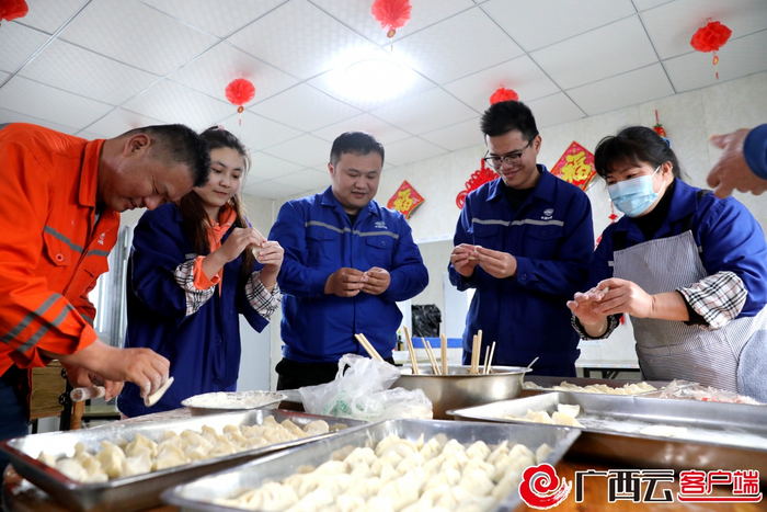 建设工人在驻地食堂包饺子准备年夜饭。