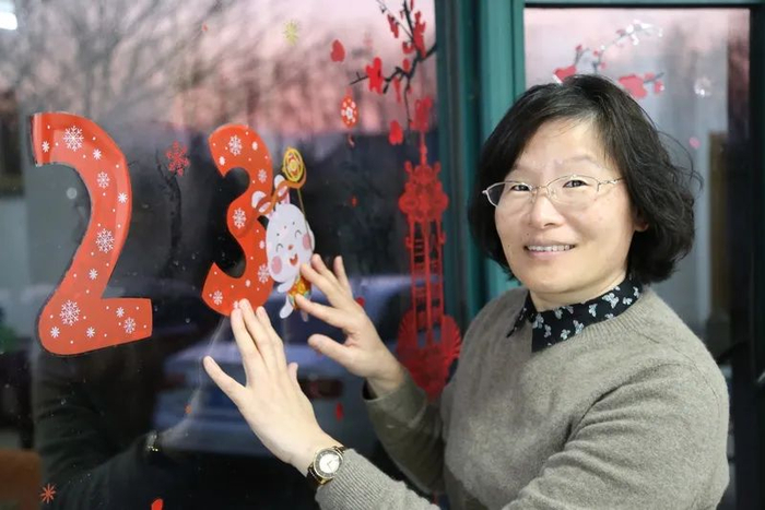 摄于1月21日，顾娟仙下班回家贴窗花。