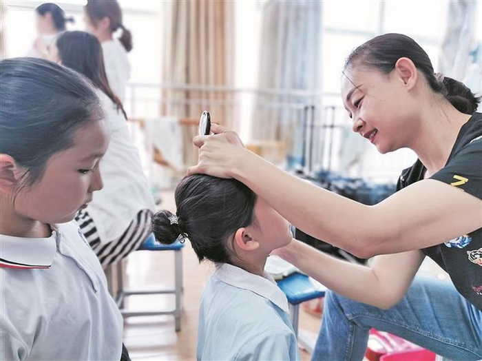     王娜给即将上台表演的孩子们化妆（资料图片）。照片由本人提供。