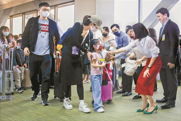     1月24日，在菲律宾马尼拉国际机场，菲律宾旅游部长克里斯蒂娜·弗拉斯科（前右二）为中国游客送上伴手礼。新华社发