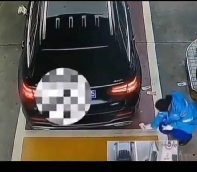 加油站员工将地上的现金捡起（视频截图）。
