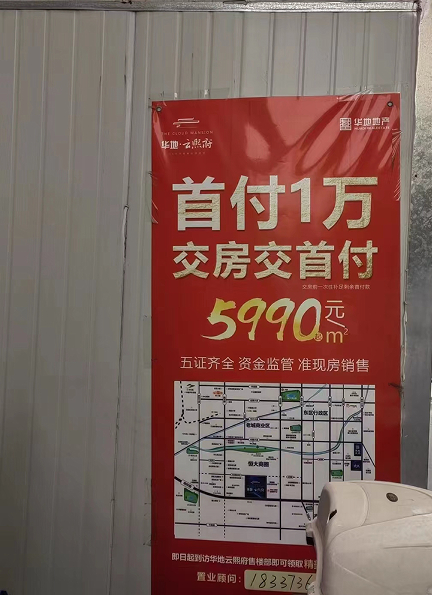 某小区门口华地云熙府项目首付1万的户外海报。 于丽丽/摄