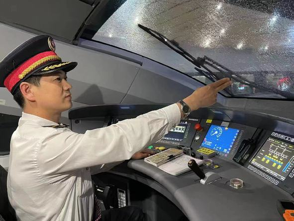 　　穆振在雨天认真操纵列车。资料照片