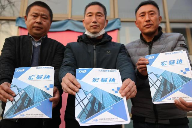 受害人霍保丰（右一）等人展示与中介公司签订的外派劳务合同。  新京报记者 李英强 摄