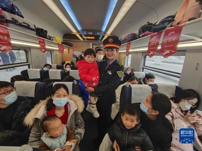 1月7日上午，C43次列车彝族列车长阿衣布卡（中着制服者）抱着小乘客。