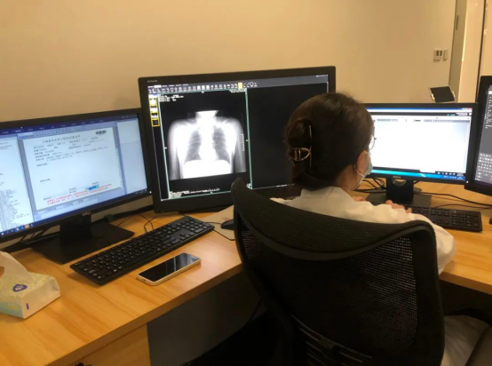 嘉定区中心医院放射科主治医正在查看电脑里社区卫生服务中心实时传输来的胸片。（图片来源：上海嘉定）