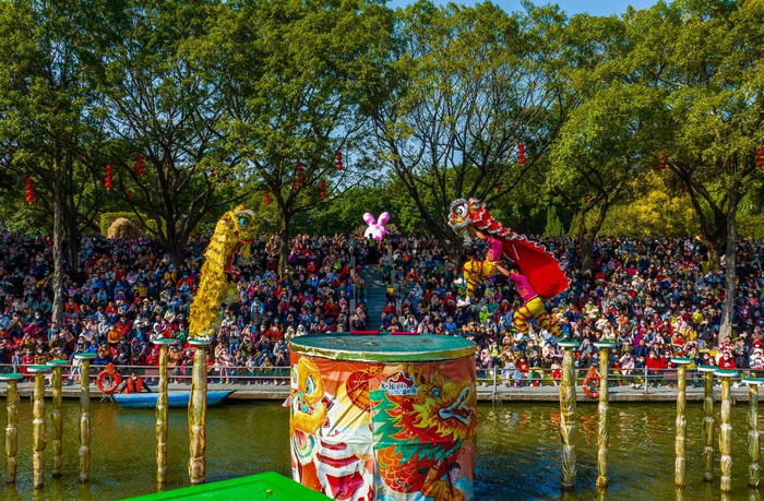 　　↑2023年1月24日，春节期间，众多游客观赏南海西樵山天湖水上高桩醒狮表演（无人机照片）。