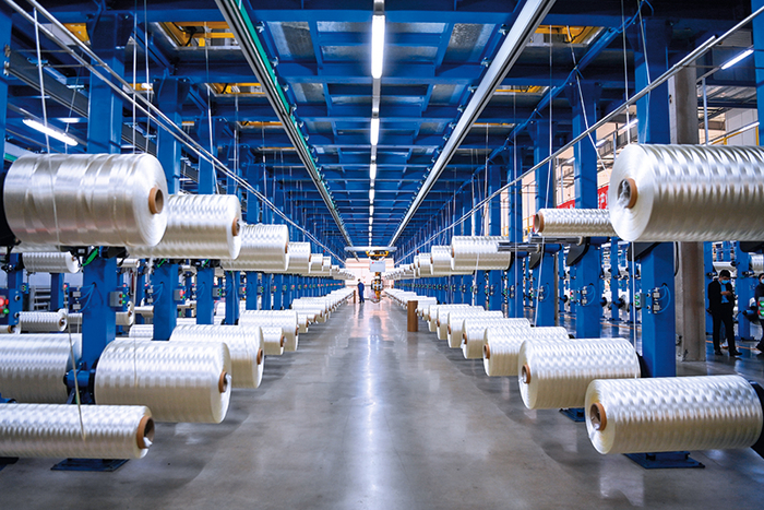 在吉林化纤集团国兴碳纤维公司生产车间内，工人整理碳纤维原丝（2022 年 10 月 31 日摄） 颜麟蕴摄 / 本刊