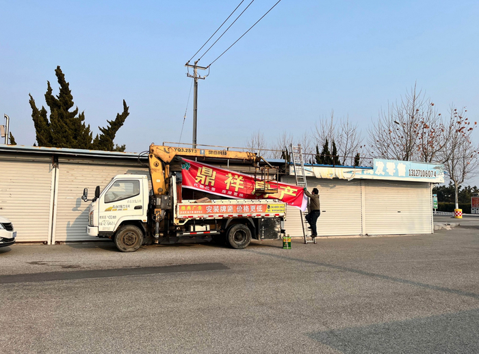 工人挂上新的招牌，时代周报记者摄