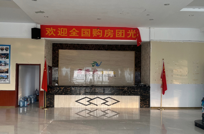 银滩一售楼处悬挂着“欢迎全国购房团光临”的横幅，时代周报记者摄