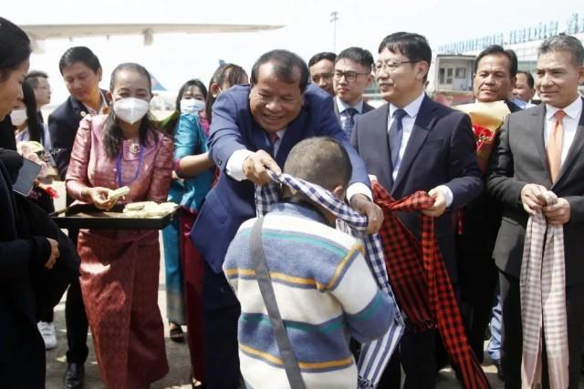 2月7日，柬埔寨旅游大臣童昆（中）在金边国际机场为中国旅客带上该国传统的高棉围巾。新华社发（批隆摄）