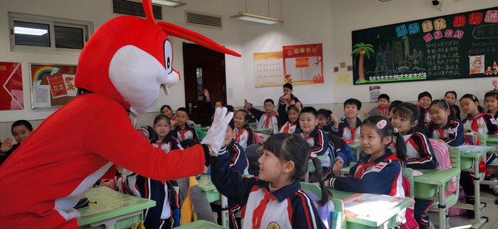 2月13日，昆明路小学老师扮演的兔形人偶在教室内与学生击掌。（受访对象供图）