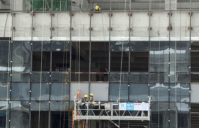 施工人员正在安装外墙玻璃。新京报记者 王颖 摄