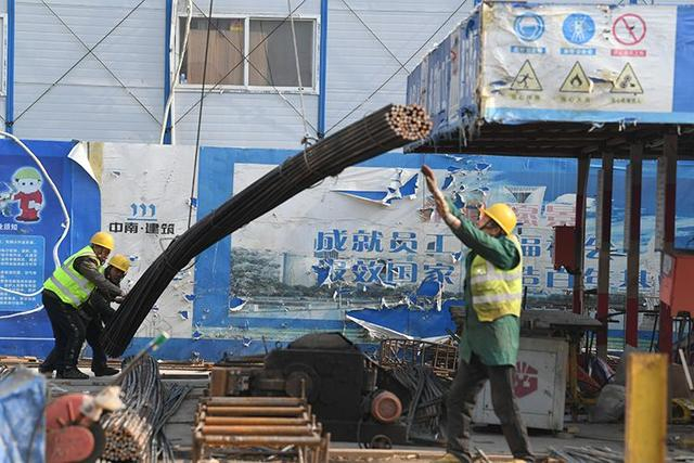 施工人员正在卸钢筋。新京报记者 王颖 摄