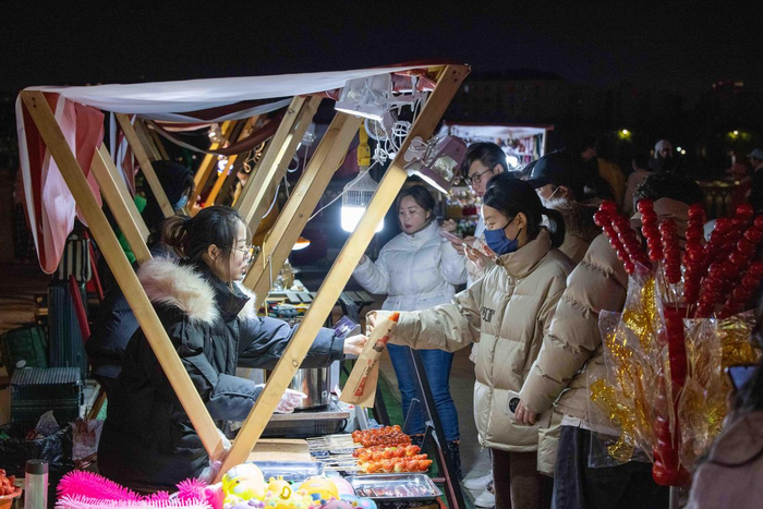 2月15日，游客在宁波老外滩步行街夜集市上购买食品。新华社记者 江汉 摄