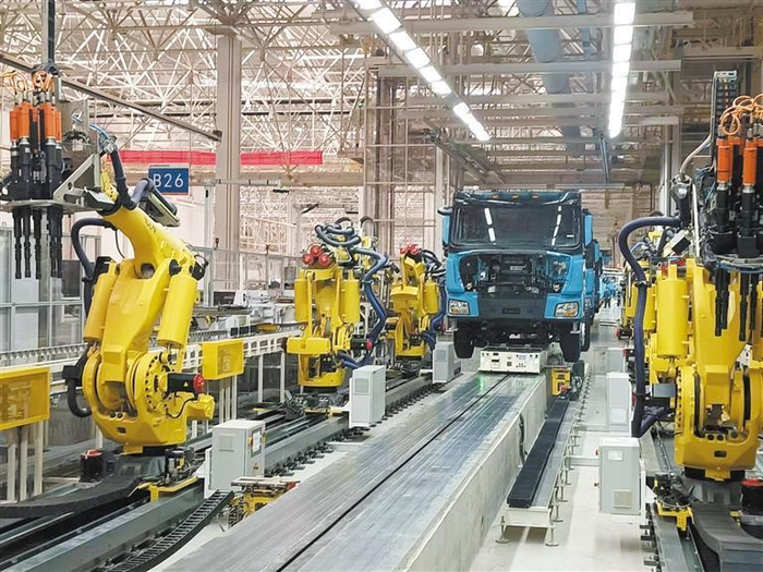 2月13日，在陕汽重卡扩能基地总装厂自动装配线上，工业机器人正在为重型卡车安装轮胎。