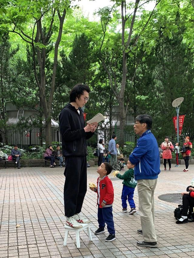 小糕的朋友正在读诗，旁边有围观的小孩一边看封面，一边吃香蕉。受访者供图