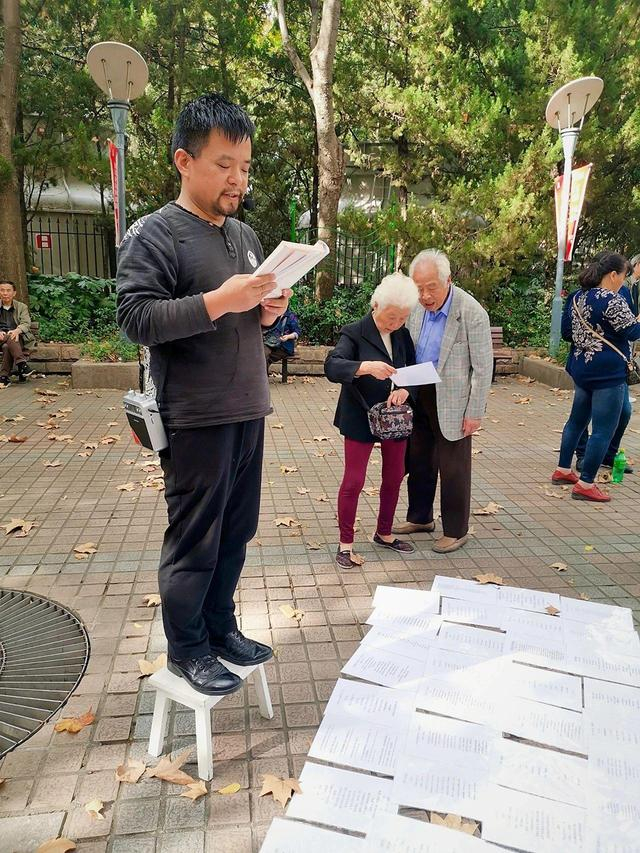 曹再飞读诗，两位白发老人正在浏览地上的诗稿。受访者供图