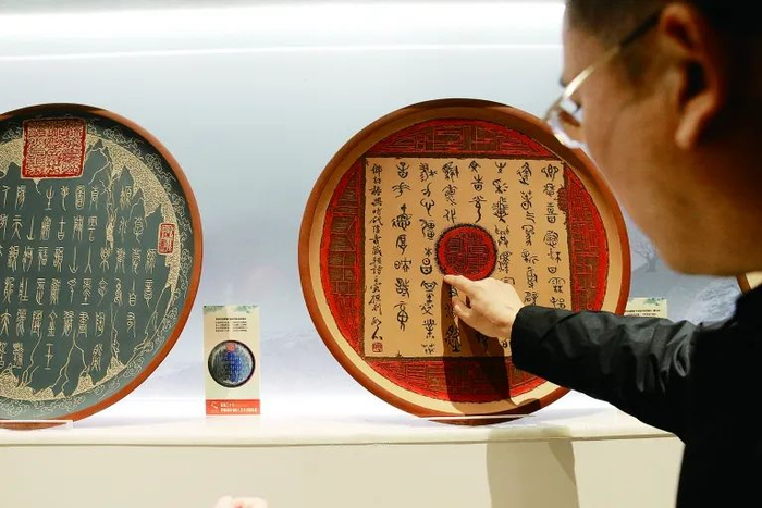 曹郁为观众讲解挂盘上的刀刻书法线条。河工新闻网记者杨磊涛摄