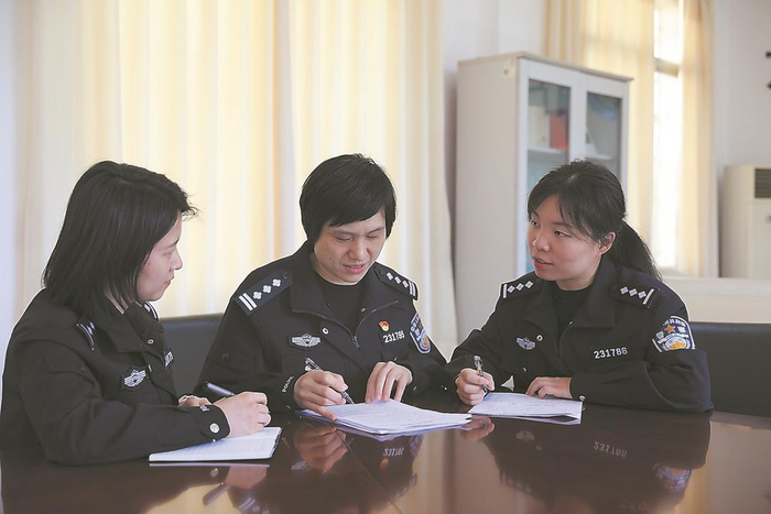 段小红（中）与同事在探讨案情。  （资料图片）