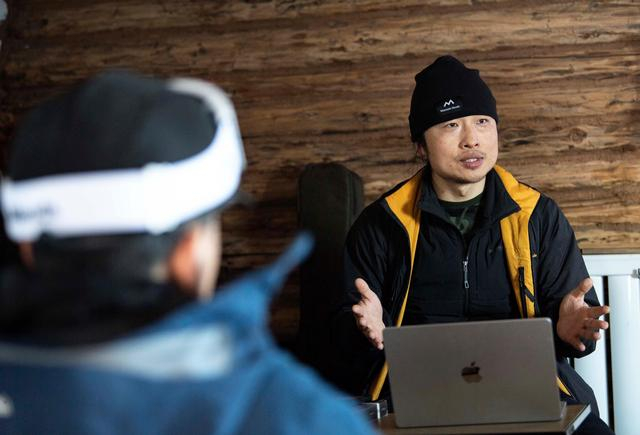 滑雪爱好者彭超在新疆阿勒泰地区禾木村与雪友分享关于安全滑雪的知识（2023年1月13日摄）。新华社记者 胡虎虎 摄