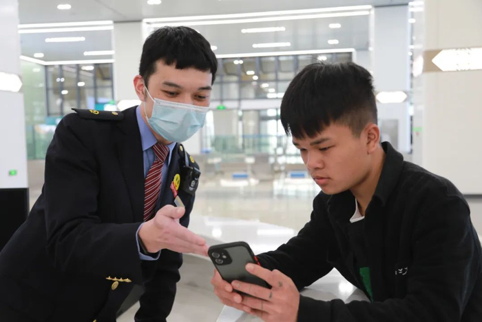 吴圩机场站工作人员引导旅客在手机购买车票。 于莉 摄