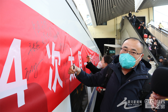 图为旅客在首发列车上签名留念