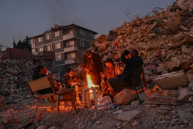 当地时间2月14日，土耳其哈塔伊，当地居民聚集在倒塌建筑旁的篝火边。图/视觉中国