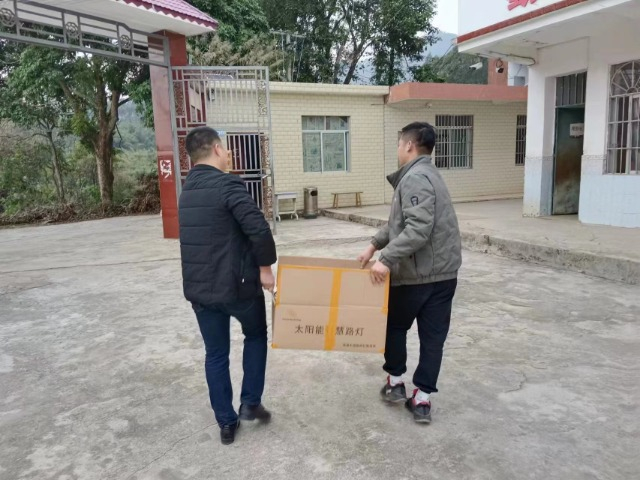 两位爱心人士将捐赠的校园照明设备搬进校园  通讯员 罗拔坤 摄