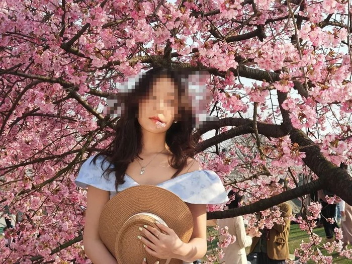 有拍照者采下樱花含在唇边拍摄