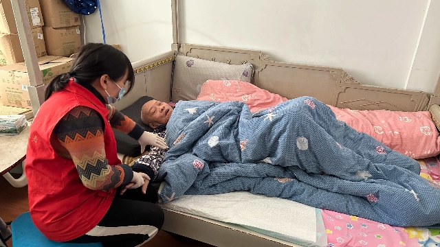 图为长护险专业护理员上门为重度失能老人做手臂按摩。 本报记者 戴梦希 摄