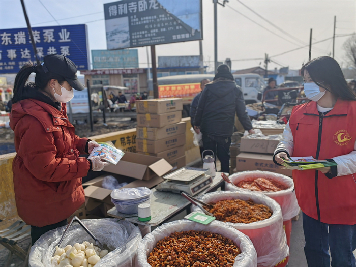 瓦房店市气象局工作人员向摆摊商贩发放《农村气象灾害避险指南》宣传材料。王雪摄影