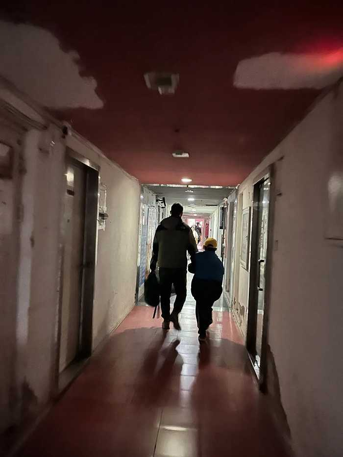 ▲爸爸带着儿子走在楼道里。