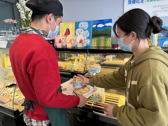 智诚手持餐盘在帮顾客选糕点