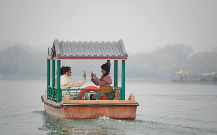 3月20日，颐和园昆明湖，游客在船上拍摄美景。新京报记者 薛珺 摄