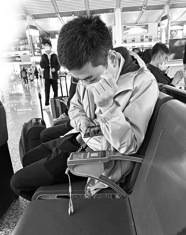 　　图：高铁站候车的乘客正在扫座椅扶手上的二维码。