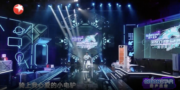 　　廖志成骑着电动自行车闪亮登场