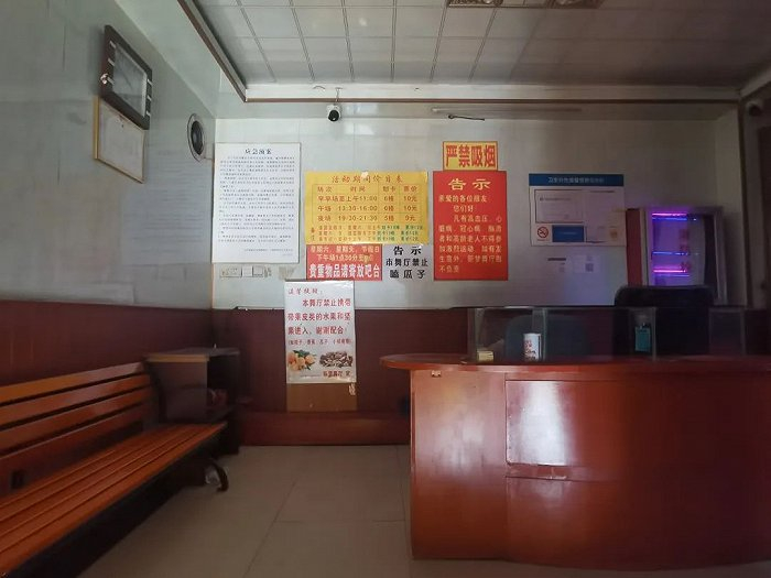 图 | 二楼的售票台是老式镶嵌着玻璃的柜台，背后的墙面上贴着温馨提示、告示、以及价格表