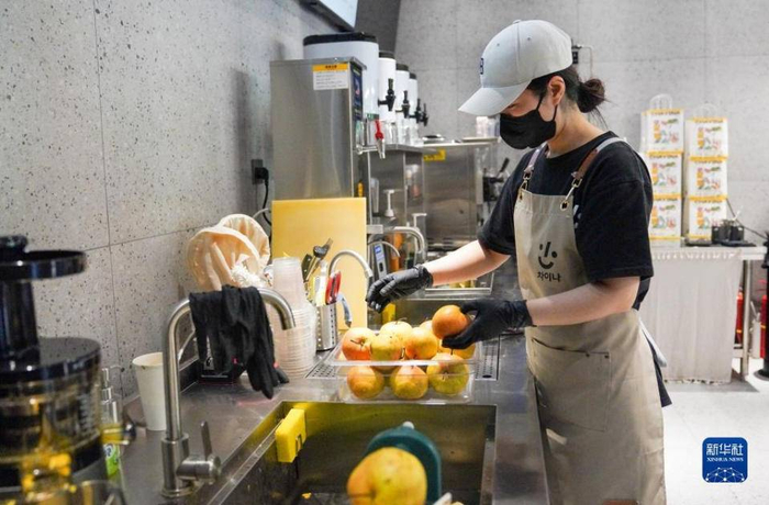 李香英在咖啡店后厨清洗苹果梨。    新华社记者  颜麟蕴  摄  