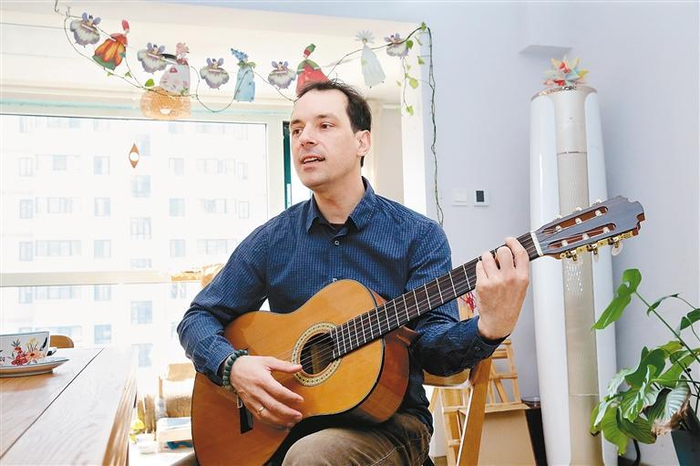 竹山在客厅一边弹吉他一边唱歌。（记者 尚洪涛 摄）