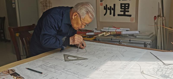 张天伟在重新绘制螃蟹风筝的机械传动原理图。记者 武丹摄