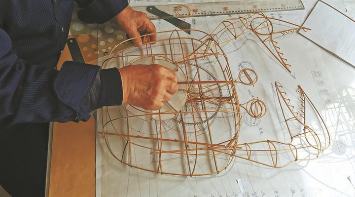 动态风筝制作的第一步是绘制机械传动原理图。图为张天伟在比照螃蟹风筝和图纸有无差异。记者 武丹摄