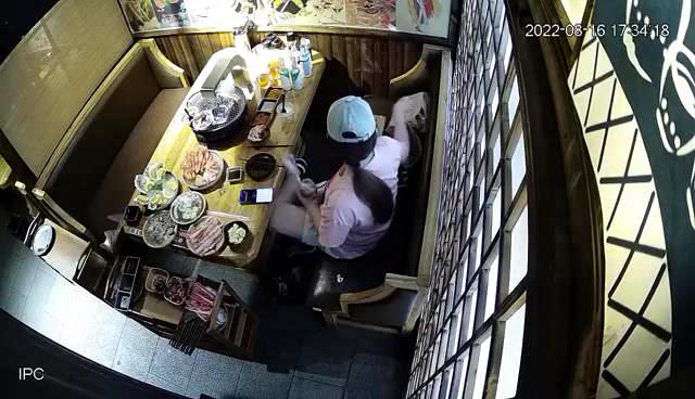 ↑监控显示，2022年8月16日，一名女子在就餐时将打包好的食材放入手提袋