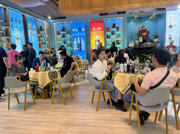 一家酱酒企业展厅内，厂家、商家、消费者围坐洽谈。