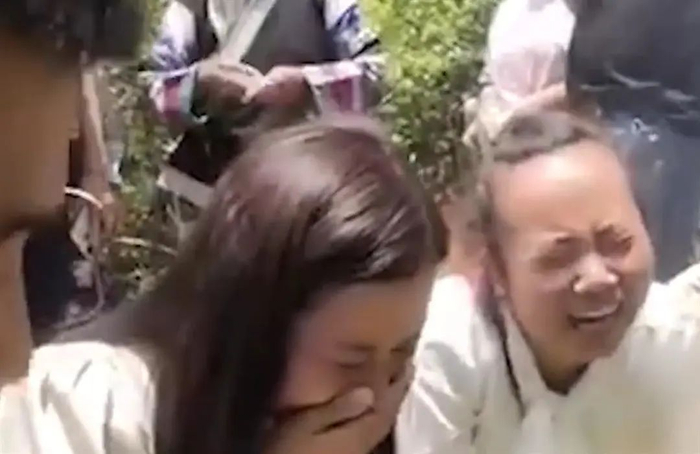 杨妞花（左）在父母坟前大哭 （视频截图）