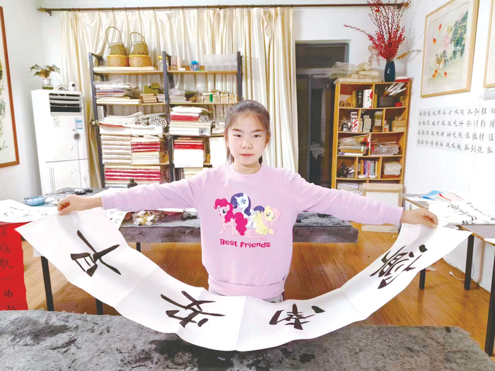     11岁的梁瀚升练习书写“早安南宁”四个字，着手准备参加活动的作品 （受访者供图）