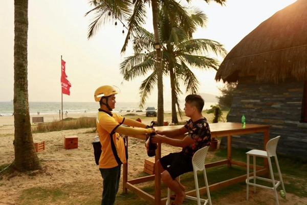 （▲图：外卖骑手把餐品送到万宁沙滩边，摄影：蔡甜）