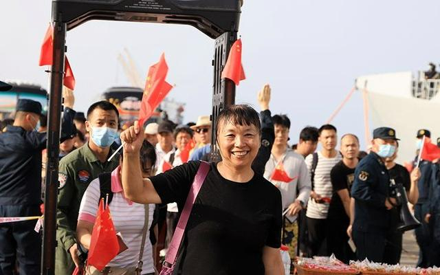 撤离人员通过安检激动挥舞国旗。通讯员 吴亢慈 摄