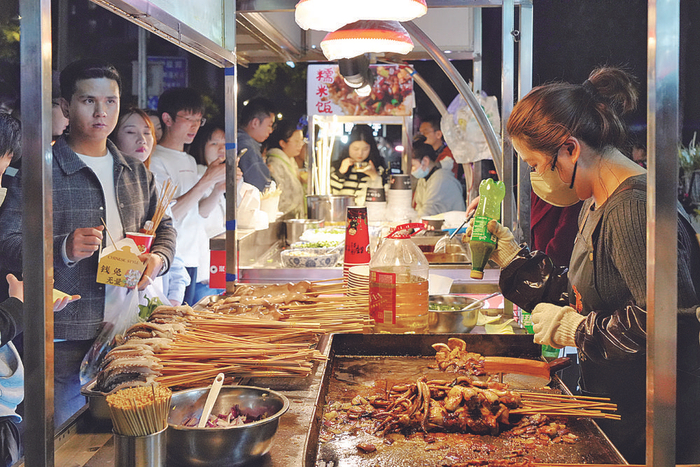     两江新区惠民路，市民正在夜市摊位购买小吃。    据重庆日报